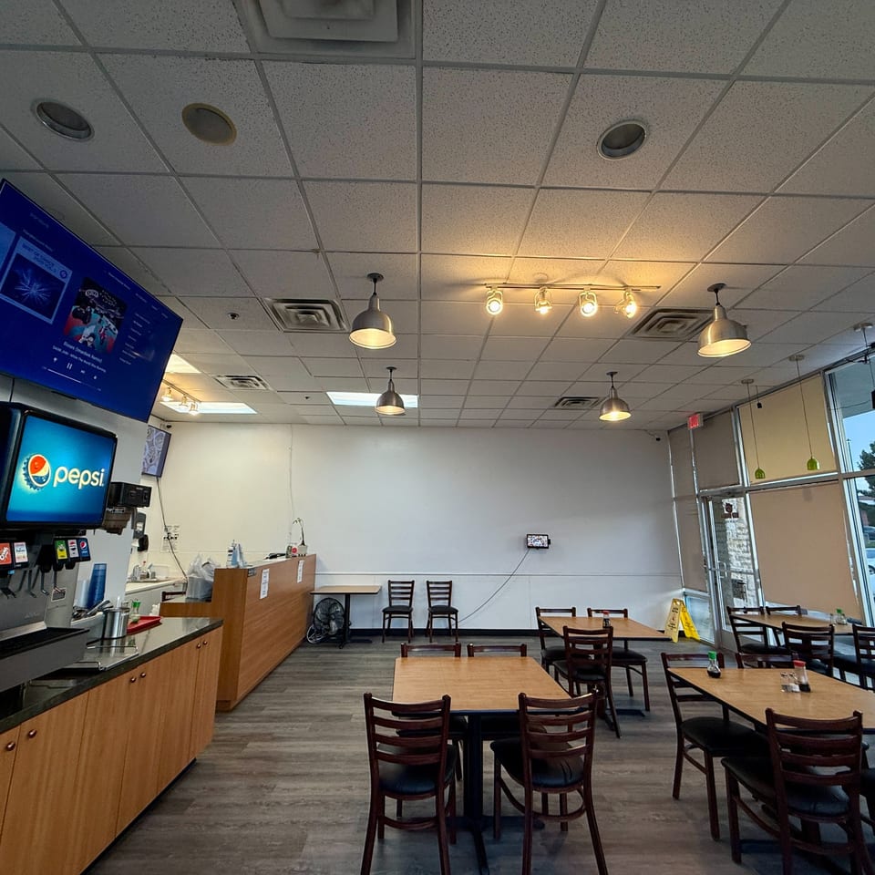 Interior of Red Panda Wok & Grill, showing dining tables, a Pepsi fountain, and a large TV screen.