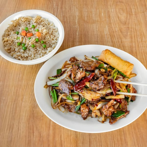Spicy beef stir-fry with onions, green onions, and red chilies, served with fried rice and an egg roll.