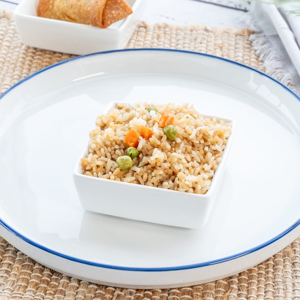 A small white square bowl of Red Panda Wok & Grill fried rice with peas and carrots.